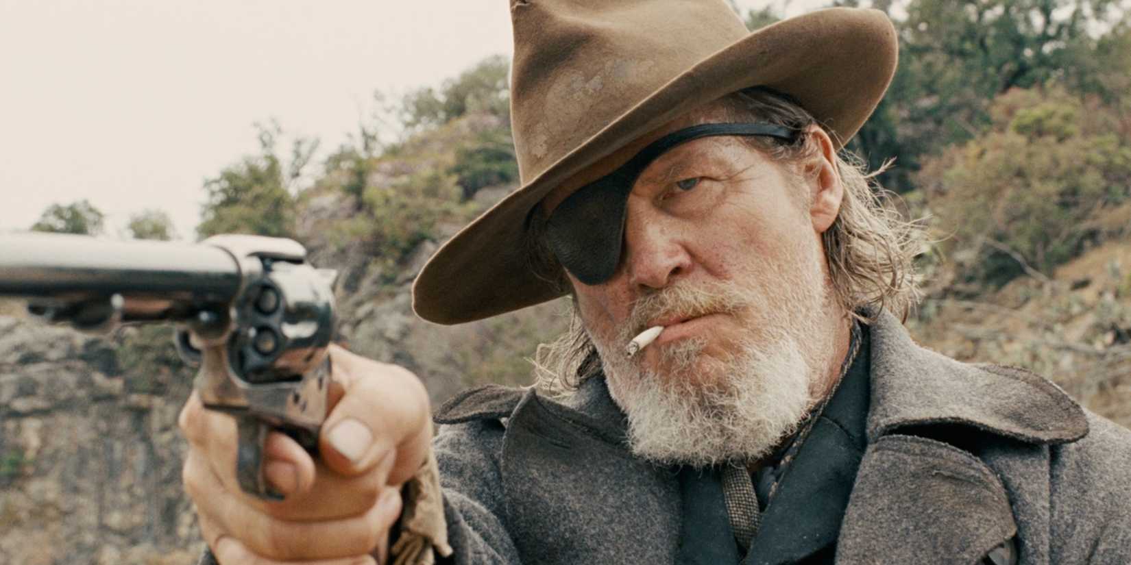 Jeff Bridges como o Xerife Rooster Cogburn em True Grit apontando uma pistola.
