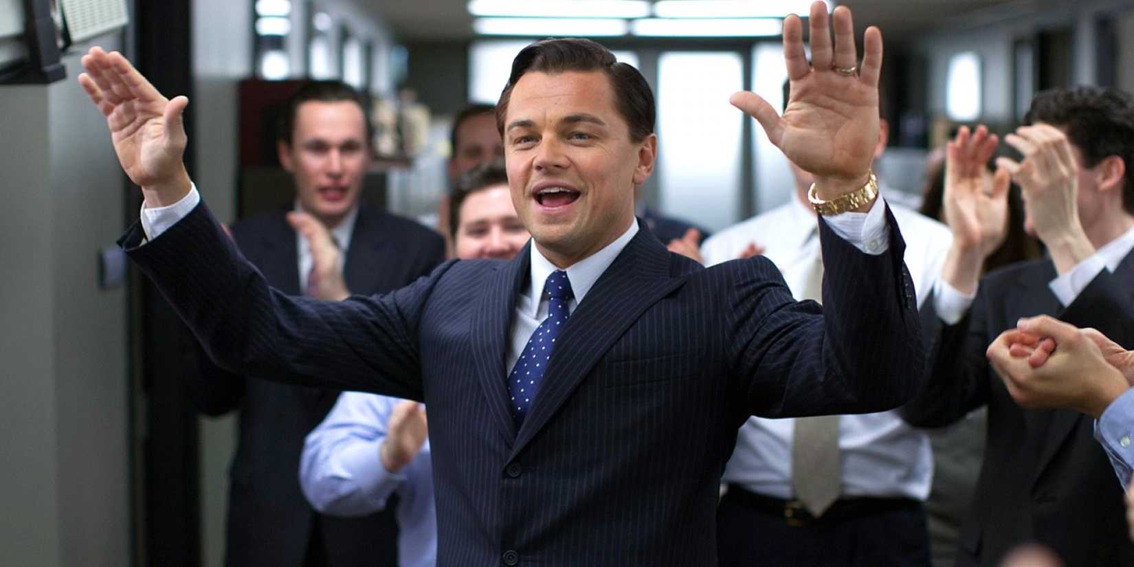 Jordan Belfort (Leonardo DiCaprio) with his hands in the air on the office floor in The Wolf of Wall Street.