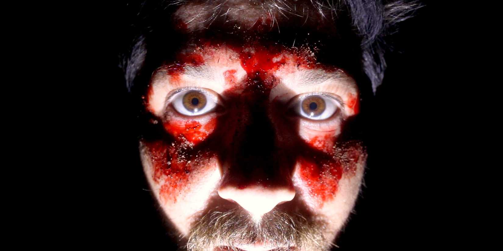 Um close-up de um homem com sangue no rosto em The Outwaters