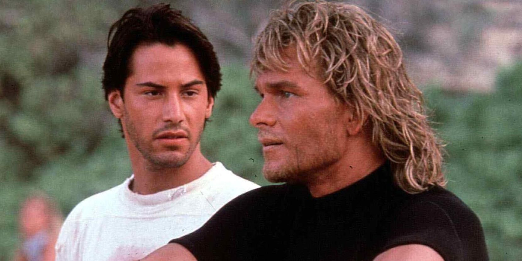 Johnny Utah (Keanu Reeves) and Bodhi (Patrick Swayze) sit on the beach in Point Break (1984).