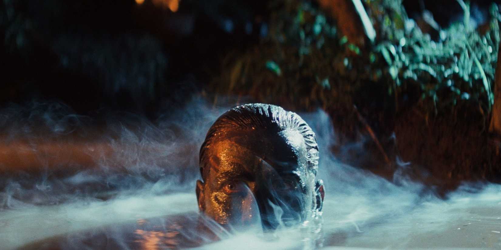 Martin Sheen as Benjamin Willard stealthily moving across a river in Apocalypse Now.
