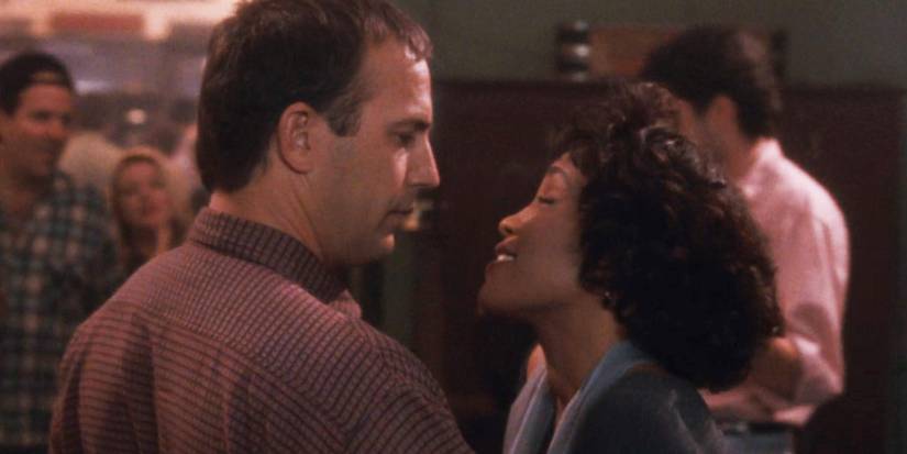 Kevin Costner as Frank and Whitney Houston staring at each other as Rachel in The Bodyguard