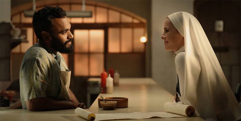 Simone (Betty Gilpin) und Jay (Andy McQueen) sitzen sich gegenüber am Tisch und lächeln einander in Mrs. Davis an