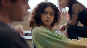 Ginny looks over at her classmate while sitting at a desk in Ginny & Georgia season 2.