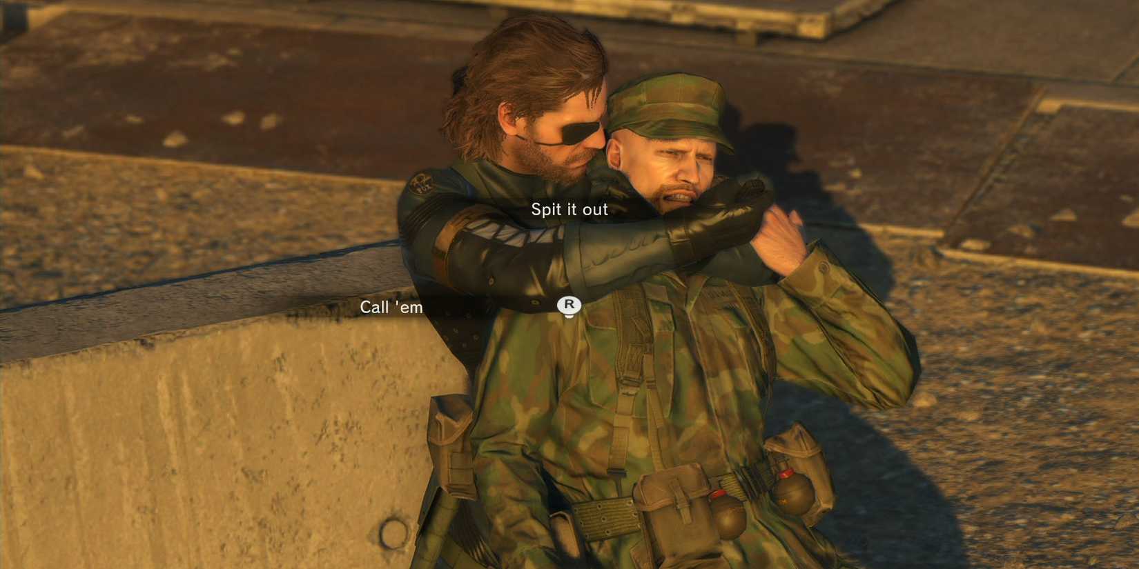 Snake holds an enemy soldier at knifepoint in a screenshot from Metal Gear Solid V: The Phantom Pain demonstrating its updated interrogation system. The menu options "Call 'em" and "Spit it out" appear on screen.