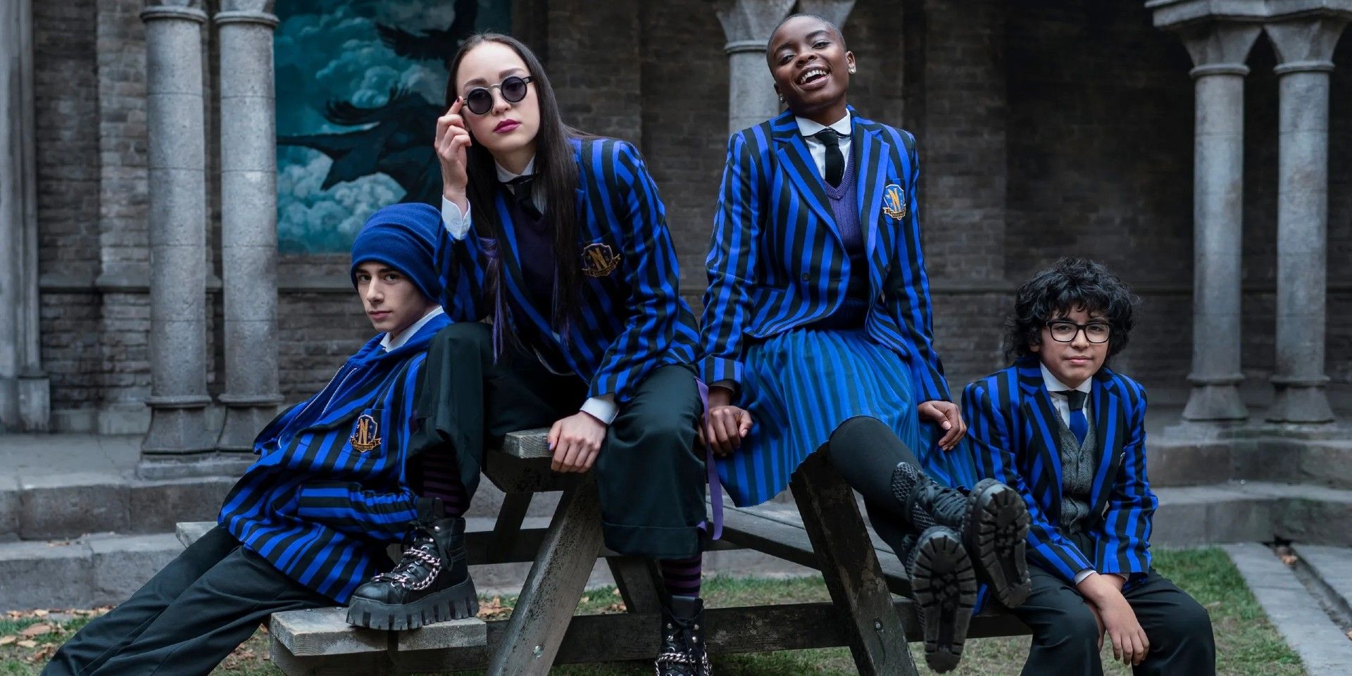 Yoko, Bianca, and other Nevermore Academy students sit on a picnic table in Wednesday.