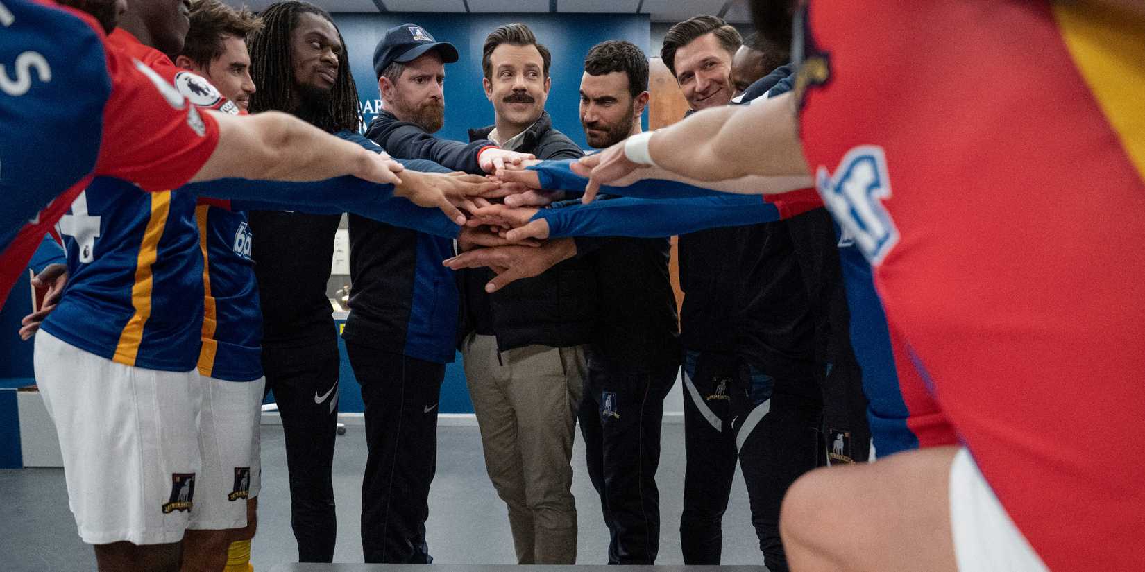 AFC Richmond putting their hands together in the locker room in Ted Lasso