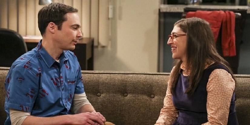 Mayim Bialk's Amy and Jim Parsons's Sheldon sitting on a couch talking in The Big Bang Theory.
