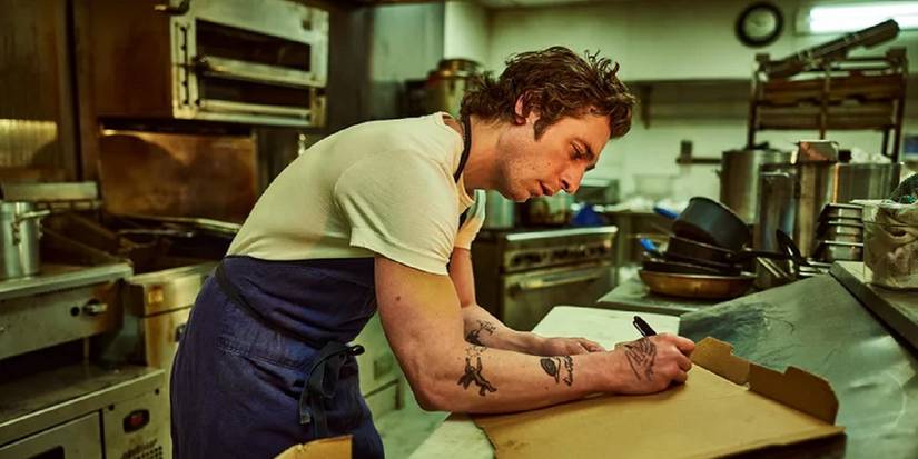 Jeremy Allen White as Carmy writing on a pizza box in The Bear