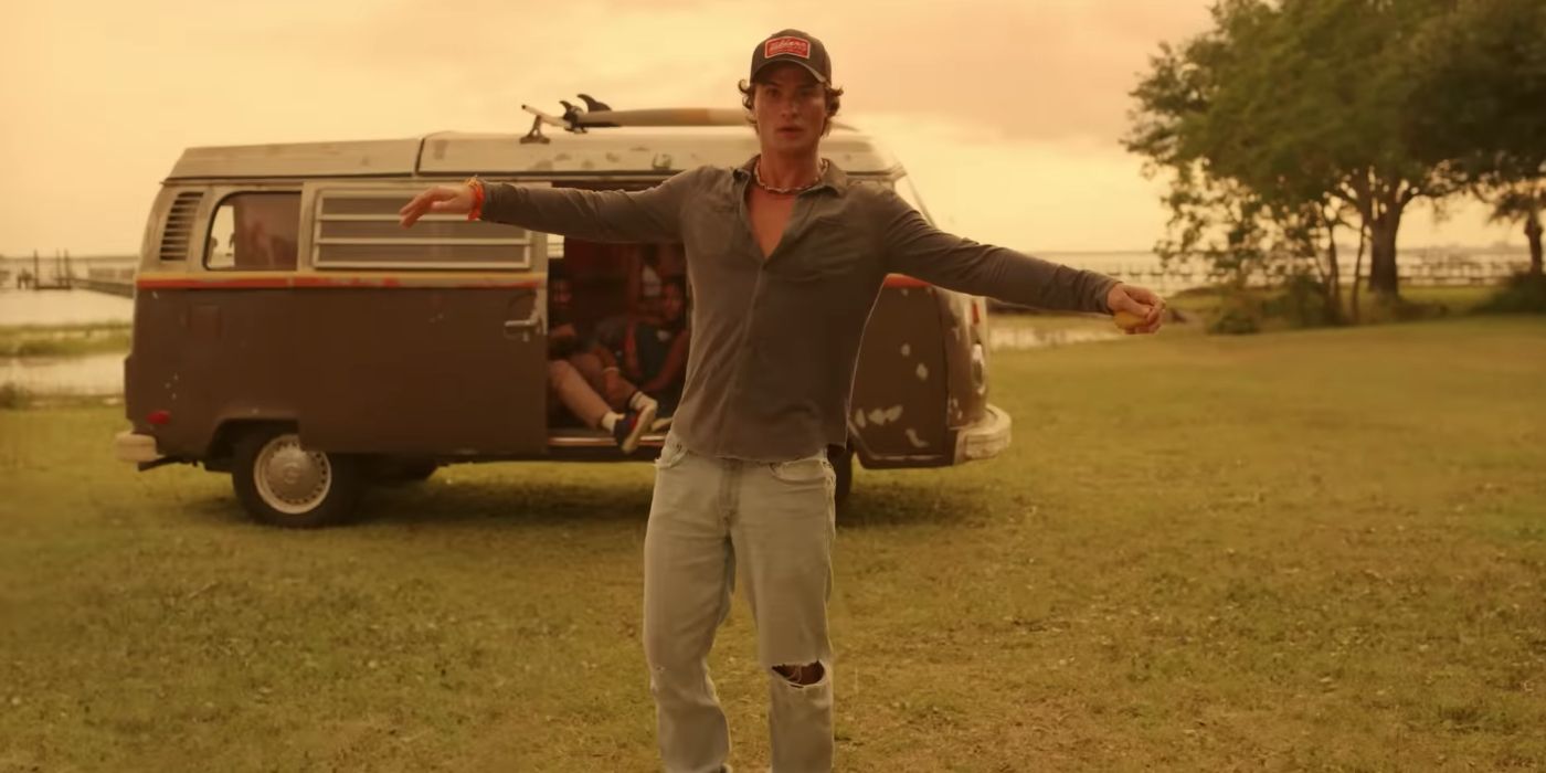 Chase Stokes as John B standing in front of the van with his arms wide in Outer Banks