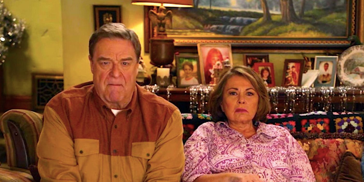 Roseanne Barr and John Goodman sitting on the couch in the Roseanne season 10 promo video