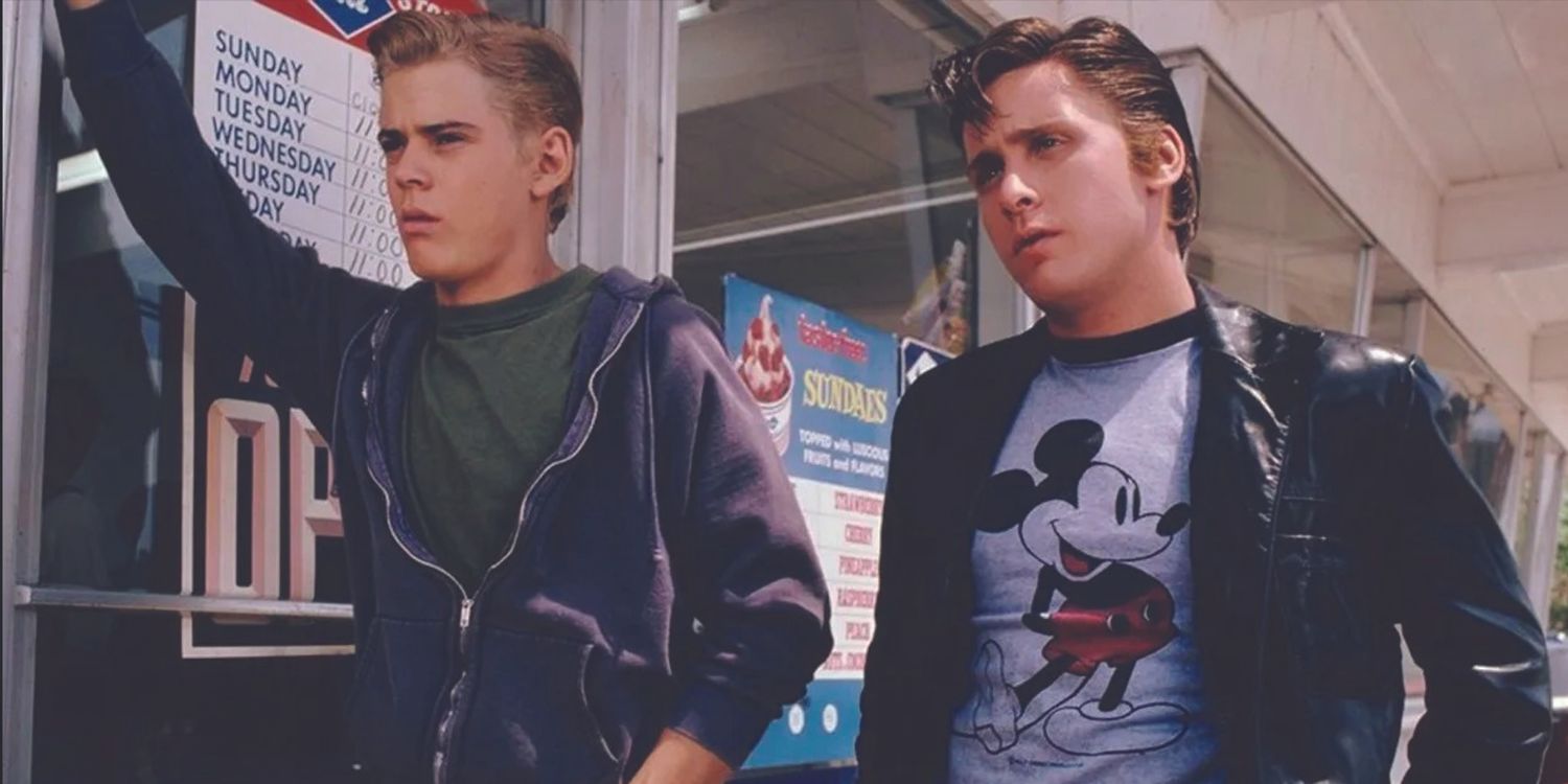 C. Thomas Howell as Ponyboy and Emilio Estevez as Two-Bit standing outside a store in The Outsiders