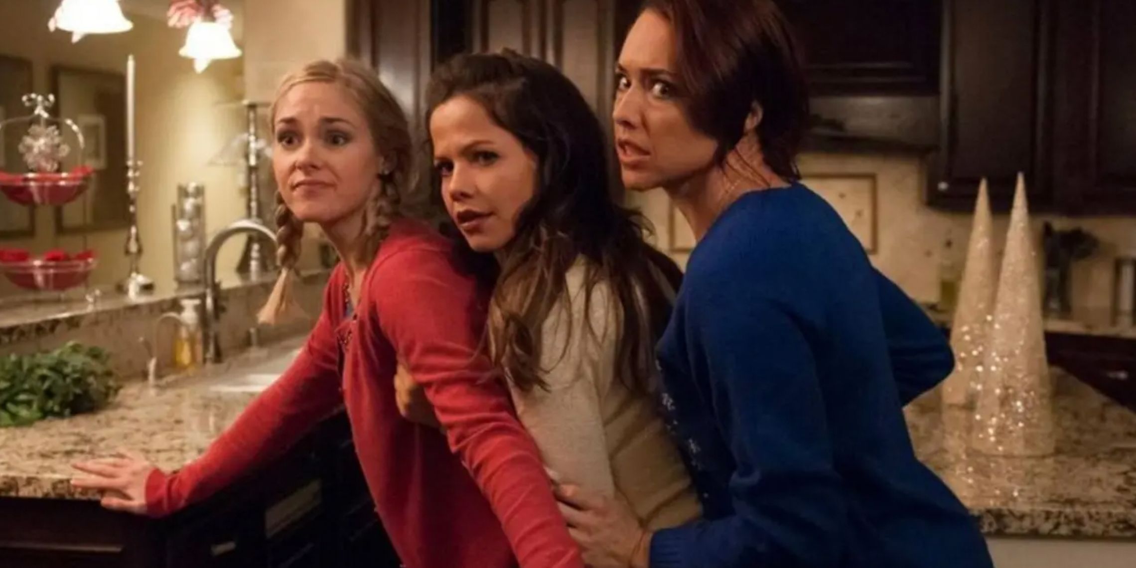 Three women leaning to see what is happening outside the kitchen in Girlfriends of Christmas Past