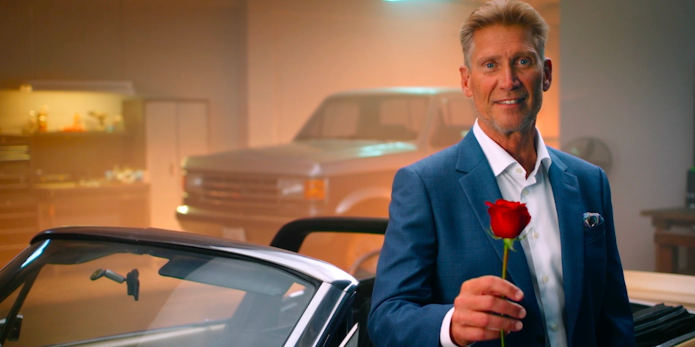 Gerry Turner Golden Bachelor holding a rose in front of old cars