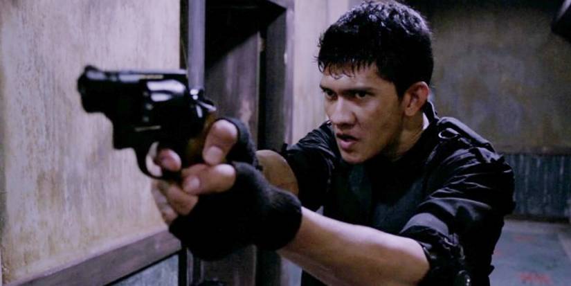 Iko Uwais apontando uma arma e parecendo raiva no ataque: redenção.