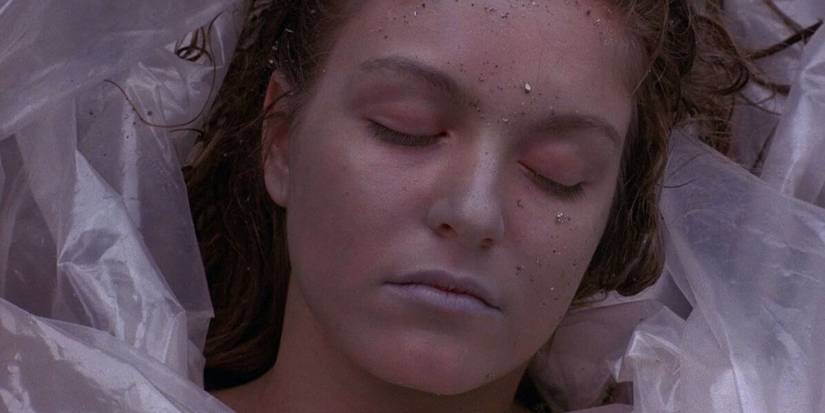 A close-up shot of Laura Palmer (Sheryl Lee) as she is found in the pilot episode of Twin Peaks. Her face is framed by plastic, her hair is wet and tangled and her lips are blue.