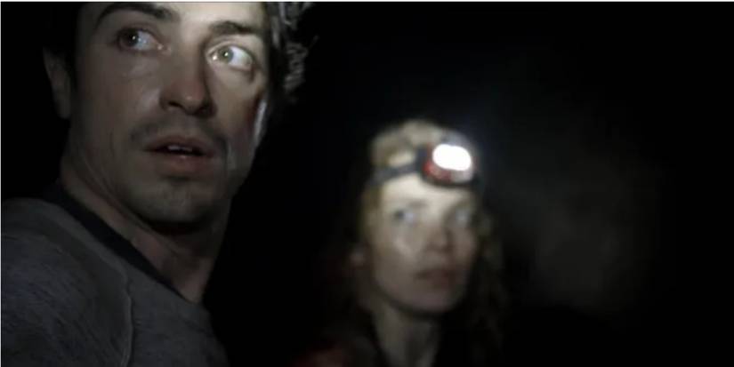 Scarlett und George blicken in „As Above, So Below“ nach links in einen dunklen Bereich.