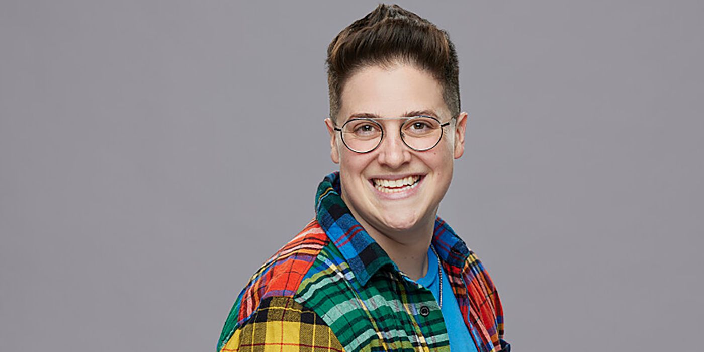 Izzy Gleicher from Big Brother in plaid shirt, smiling, in front of gray background