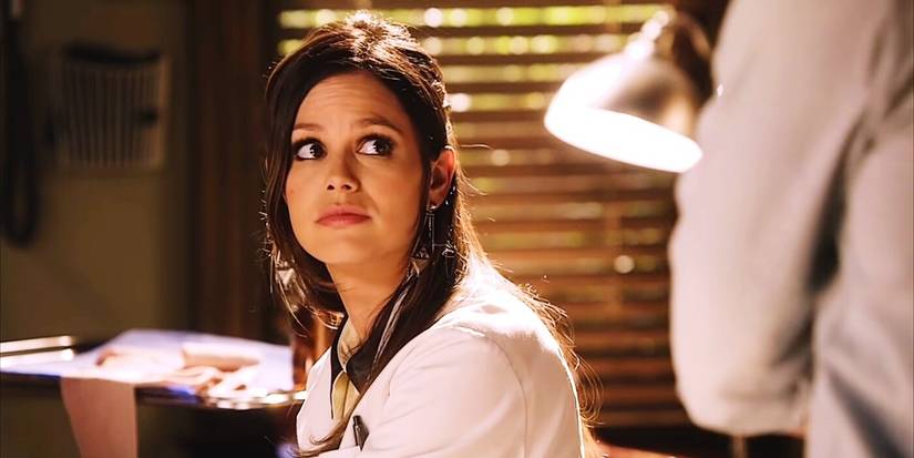 A scene from Hart of Dixie featuring Rachel Bilson as Dr. Zoe Hart, wearing a white doctor's coat and looking off to the side at someone.