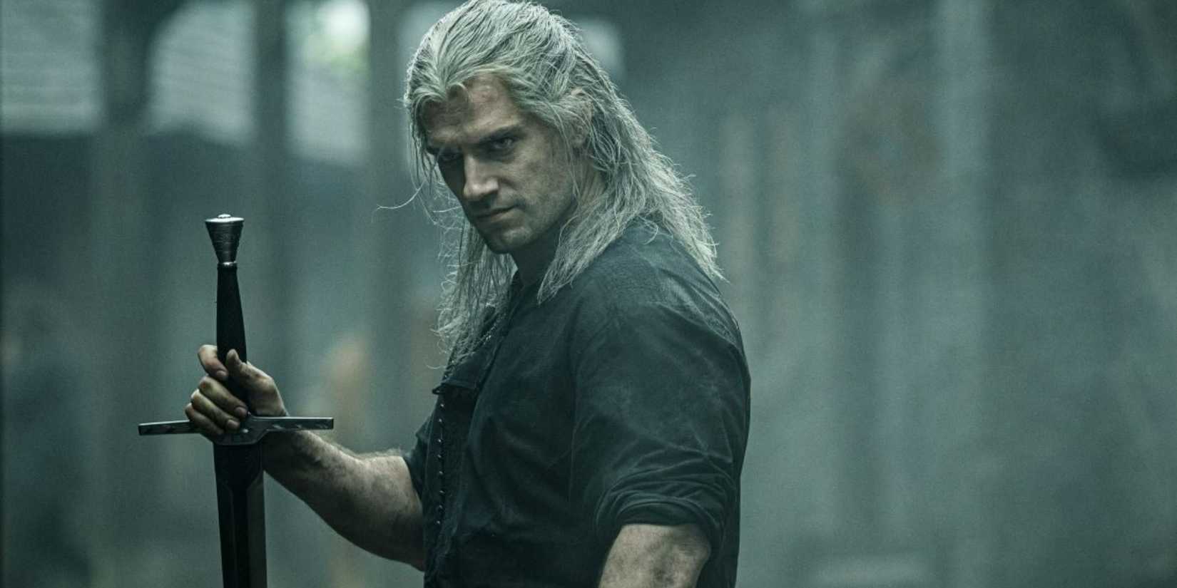 Henry Cavill as Geralt of Rivia holding a sword in The Witcher.