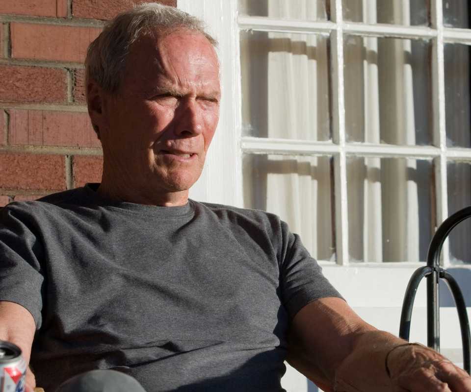 Clint Eastwood as Walt Kowalski sits on a porch in Gran Torino