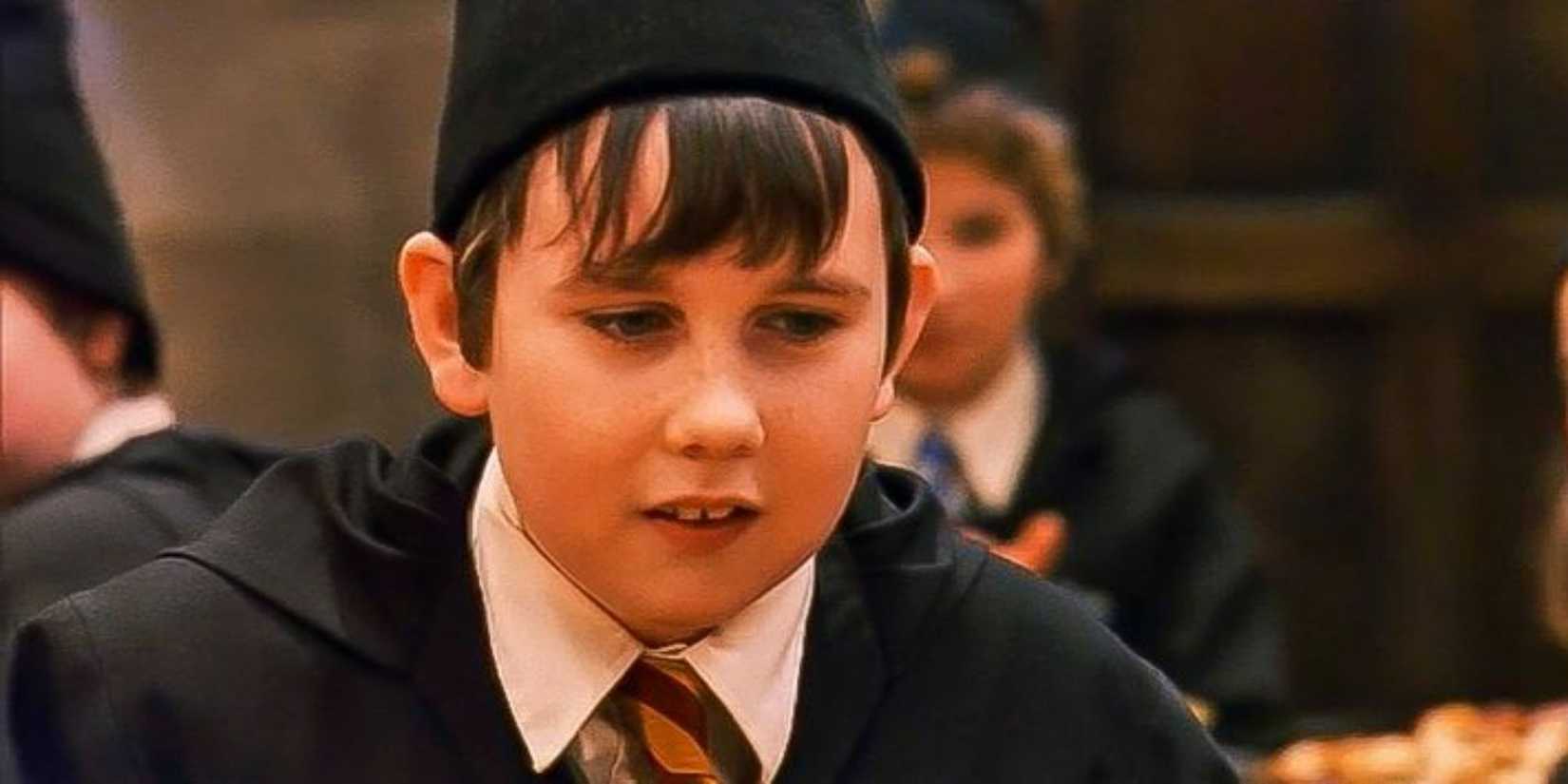 Neville Longbottom wears his robes and a hat.