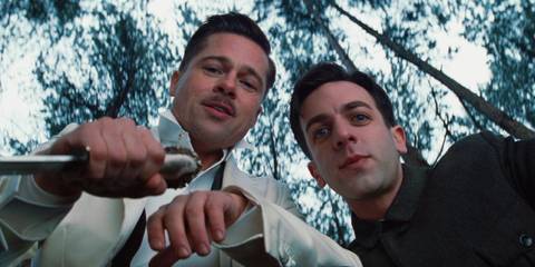 Brad Pitt and BJ Novak look down at someone menacingly in the woods in Inglourious Basterds