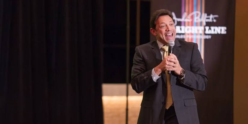 Jordan Belfort as the Auckland Straight Line host speaking into a microphone in The Wolf of Wall Street