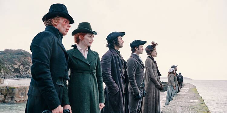 Ross (Aidan Turner) and Demelza (Eleanor Tomlinson) look at the ocean alongside several others in Poldark