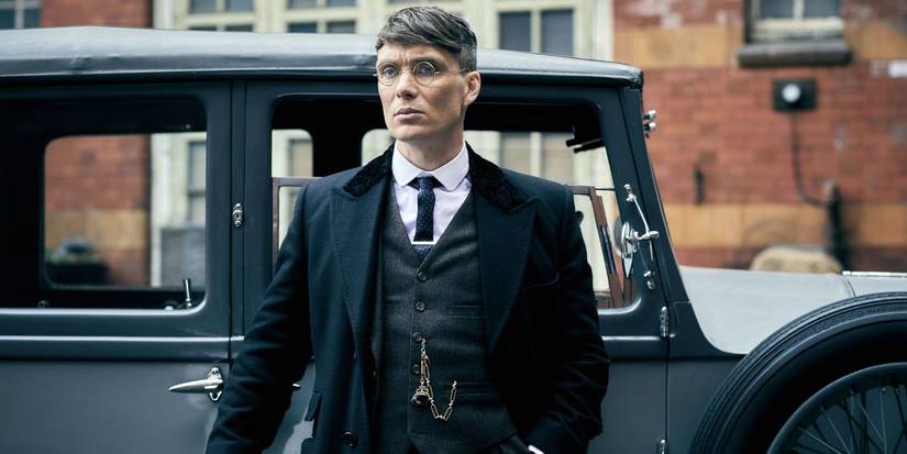 Cillian Murphy as Tommy Shelby standing outside a car in Peaky Blinders.