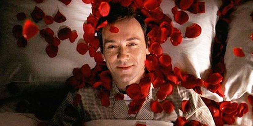 Cena final de American Beauty com Kevin Spacey como Lester Burnham deitado na cama com pétalas de rosa caindo sobre ele.