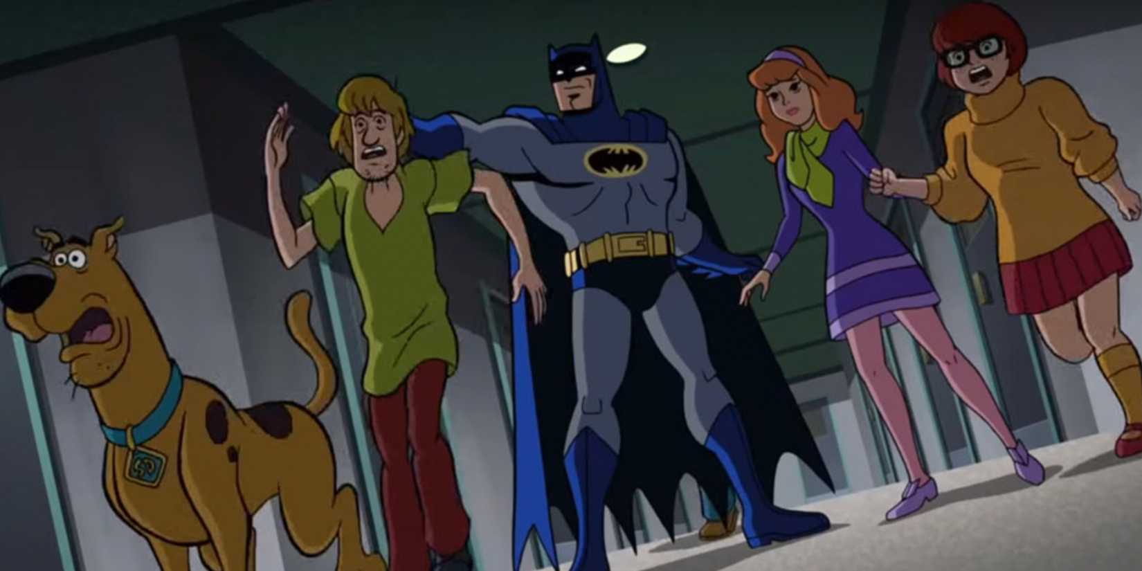 Batman holds onto Shaggy while Velma Daphne and Scooby Doo look surprised in Scooby Doo and Batman The Brave and the Bold