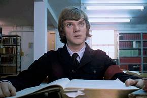 Alex (Malcolm McDowell) sitting at a table in the library in A Clockwork Orange