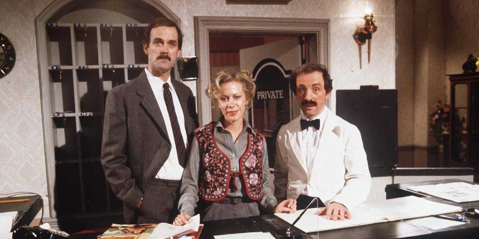 Os personagens de torres de Fawnty parecendo confusos atrás da mesa