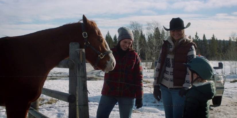 Amy and another woman smile as Lyndy approaches a horse in Heartland