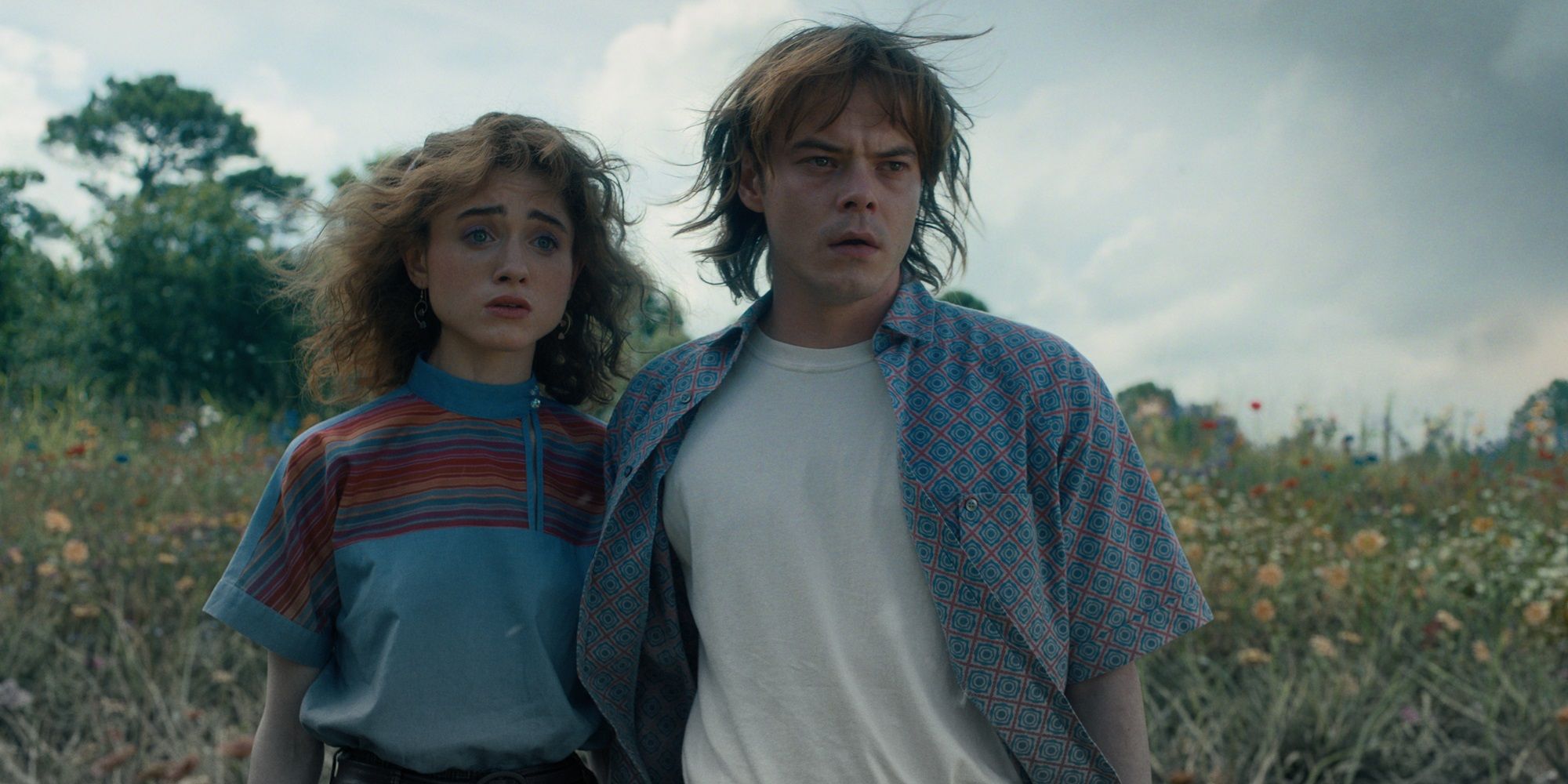 Charlie Heaton's Jonathan and Natalia Dyer's Nancy looking concerned in a field in Stranger Things season 4 finale