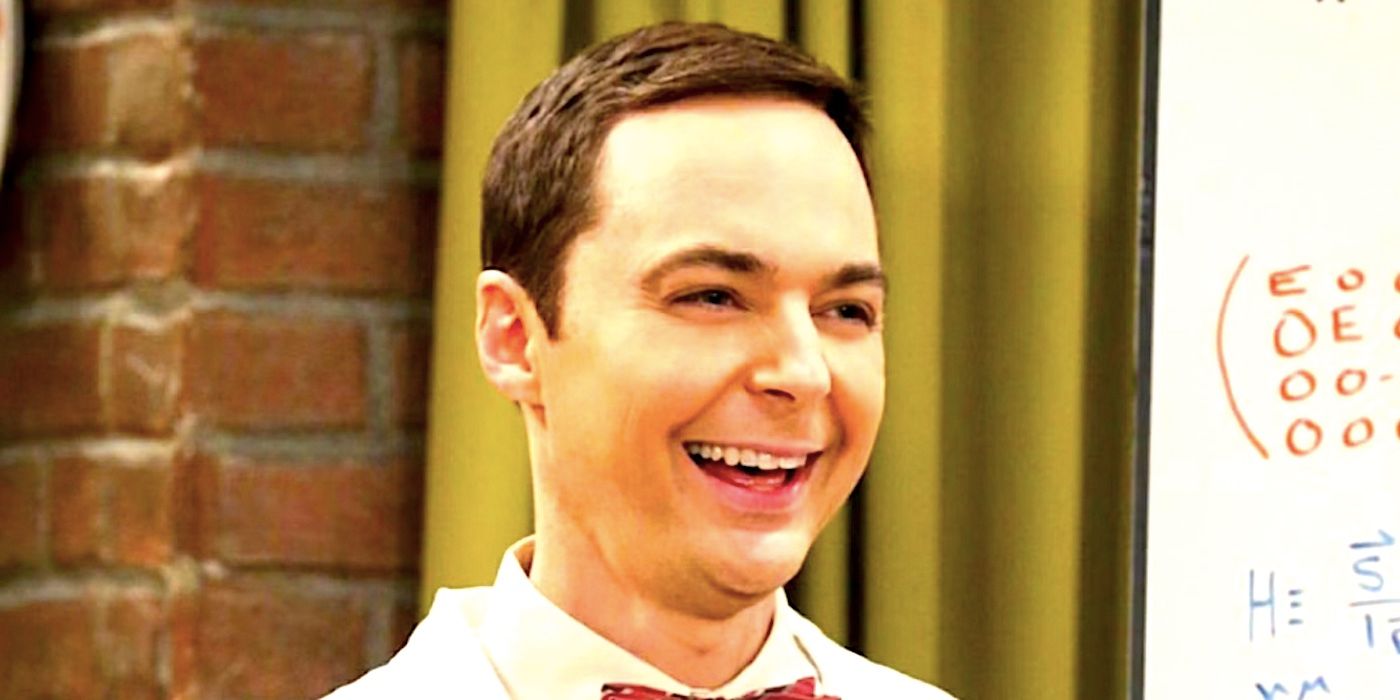 Sheldon Cooper smiling and laughing while wearing a bow tie in front of a white board in The Big Bang Theory