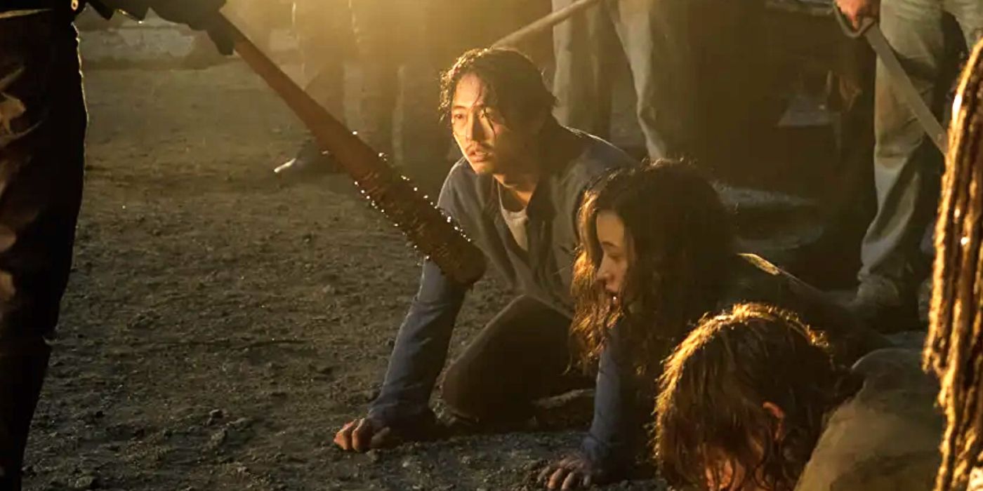 Steven Yeun kneeling on the ground as Glenn looking at a baseball bat in The Walking Dead season 7.