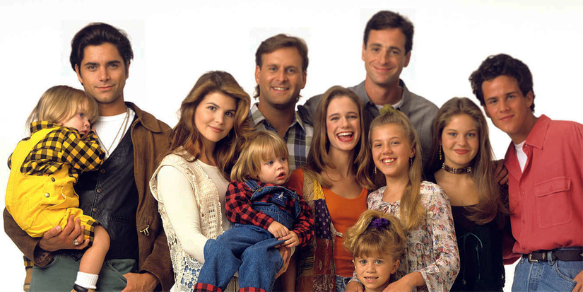 The cast of Full House posing and smiling.