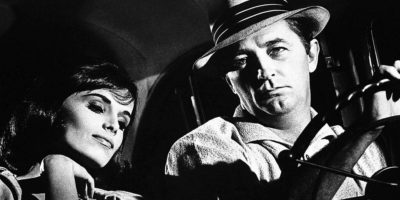 Robert Mitchum driving as a woman sleeps on his shoulder in Cape Fear