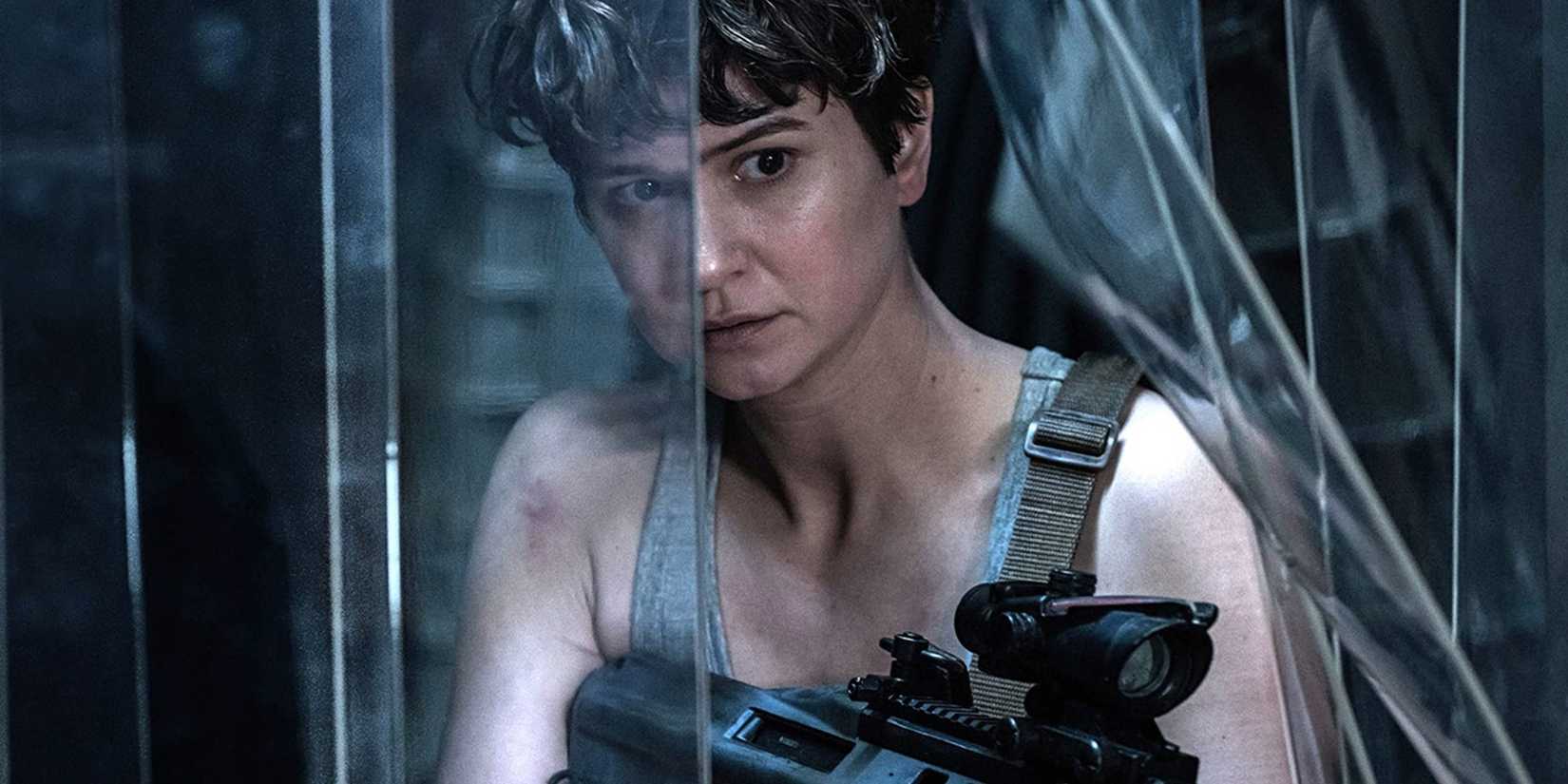 Katherine Waterston as Daniels pushing through plastic sheeting with a gun in Alien: Covenant