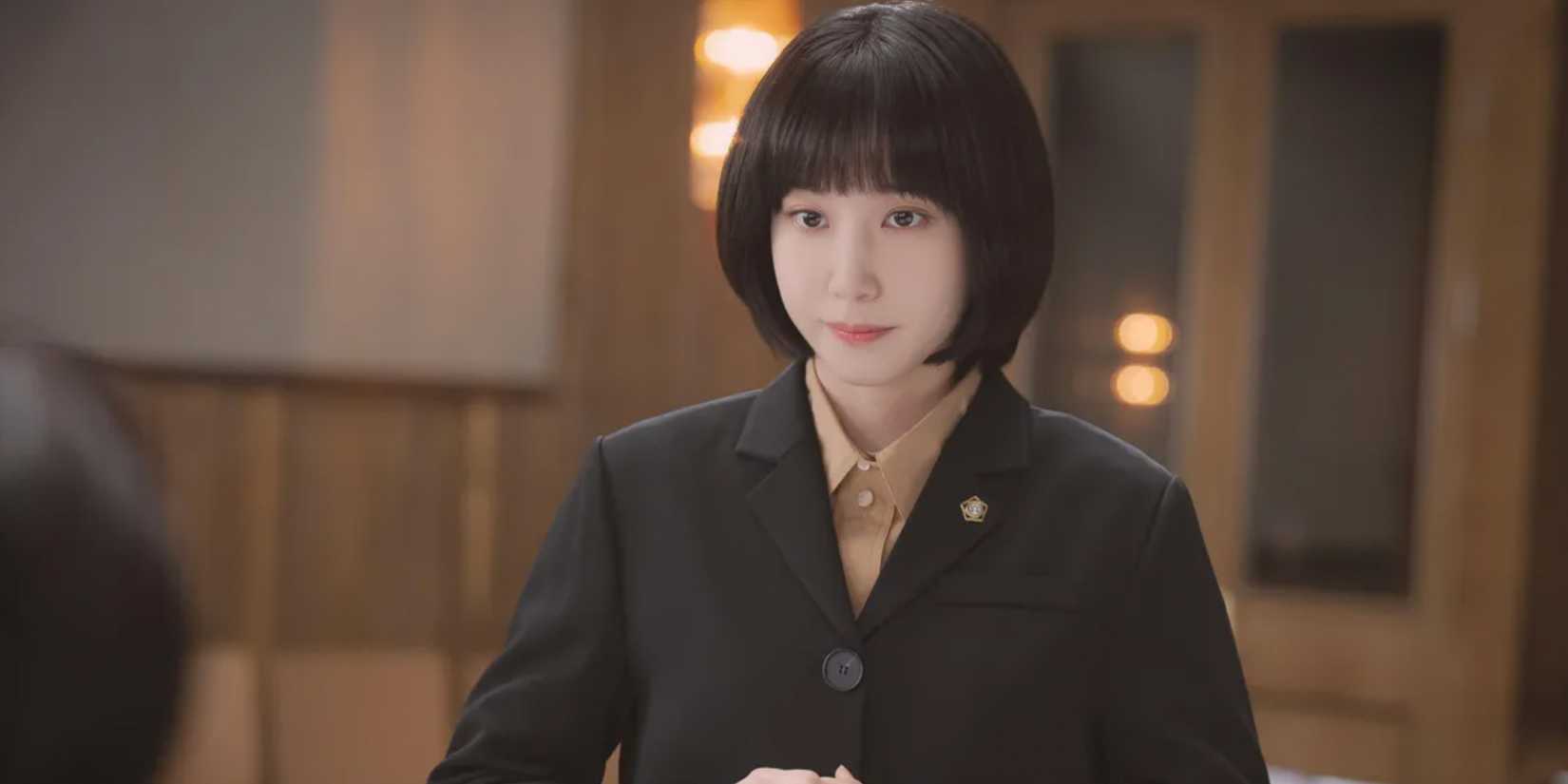 Advogada Extraordinária Woo em um terno preto no tribunal.