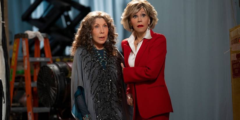 Grace (Jane Fonda) and Frankie (Lily Tomlin) standing in a TV studio, holding each other and looking nervous in Grace and Frankie.