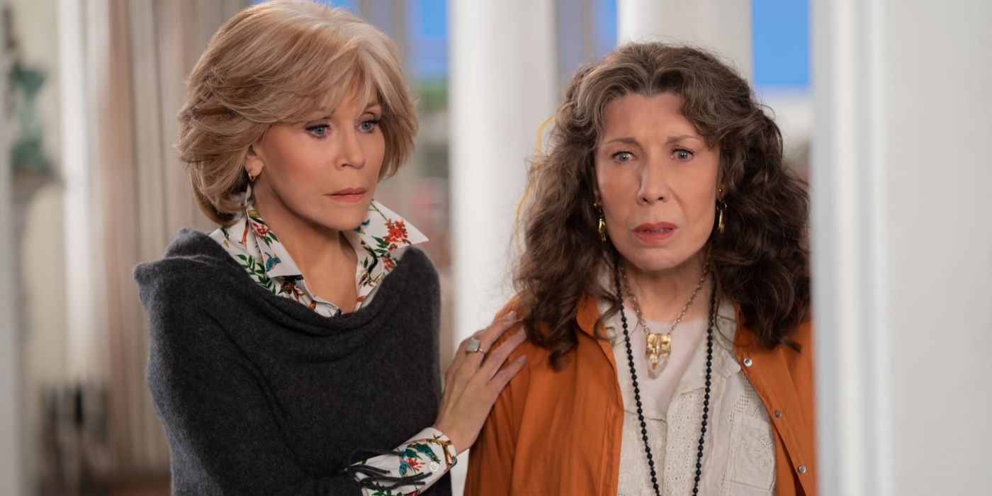 Grace (Jane Fonda) with her hand on Frankie's (Lily Tomlin) shoulder, both looking concerned in Grace and Frankie