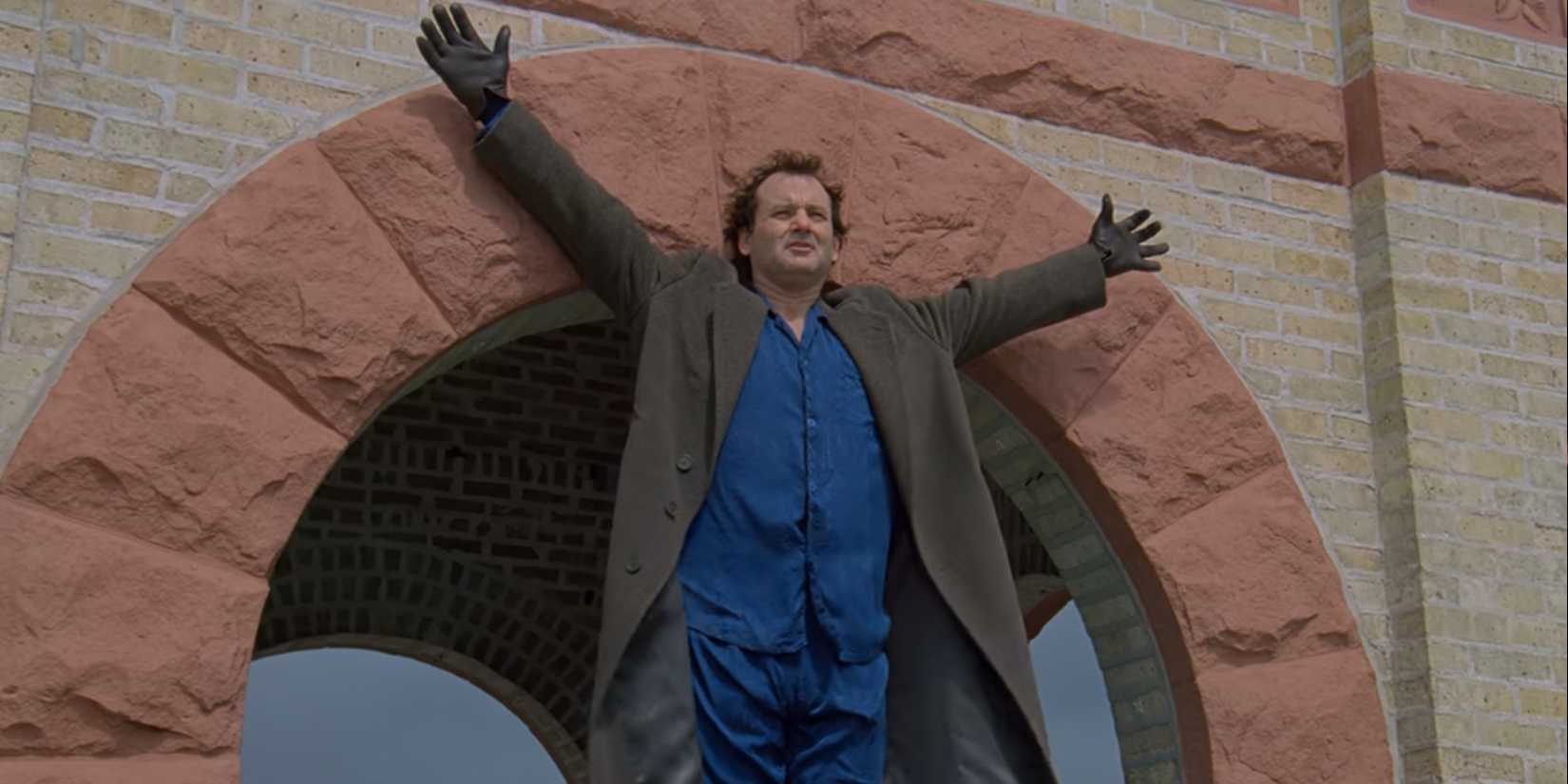 Phil (Bill Murray) estica os braços enquanto se prepara para pular de uma torre em Groundhog Day.