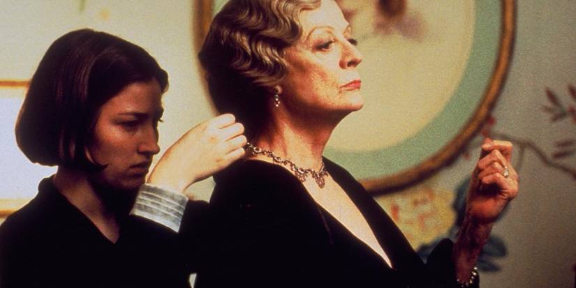 A young woman putting a necklace around Maggie Smith as Countess Constance's neck in Gosford Park