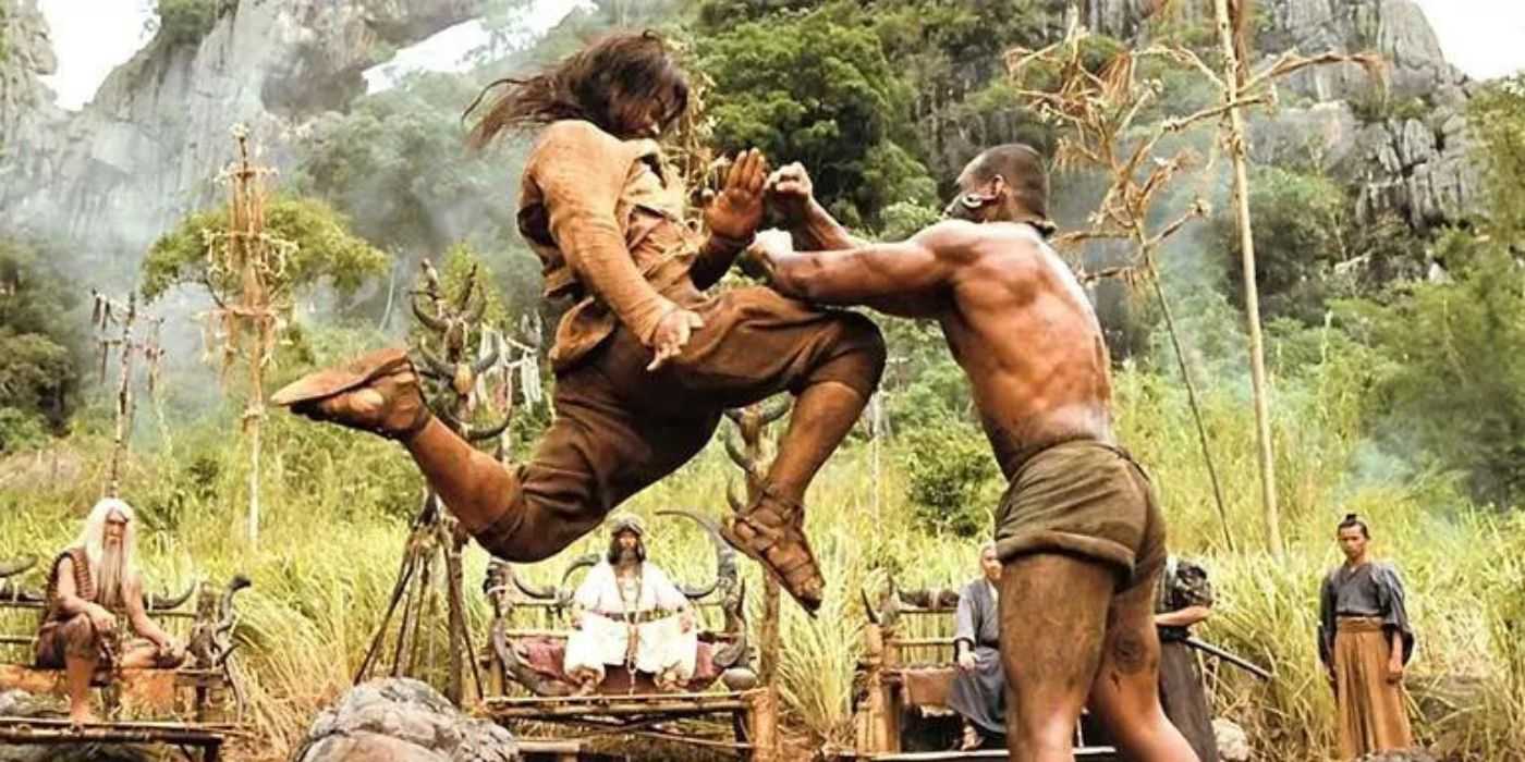 Tien launching a flying knee at a shirtless opponent in front of keen observers in Ong Bak 2