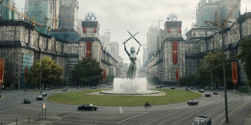 An image of a fountain, buildings, and cars in Panem in The Hunger Games: The Ballad of Songbirds and Snakes