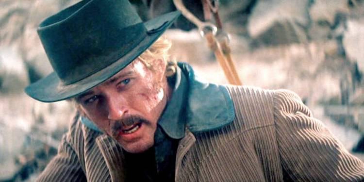 Robert Redford as The Sundance Kid looking exhausted and defeated while seated at a campsite in 1969's Butch Cassidy and the Sundance Kid