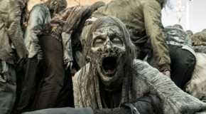 A growling zombie in The Walking Dead next to other zombies